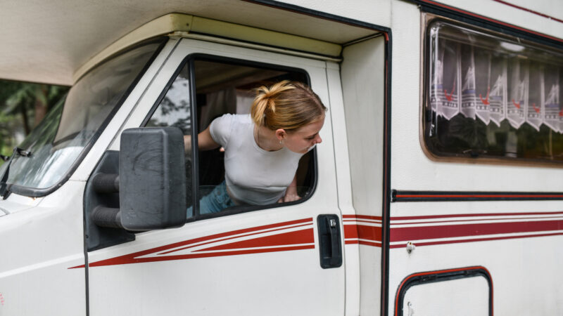 A woman looking back to back out of a spot while driving an RV