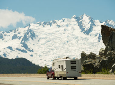 An RV driving past snowy mountains