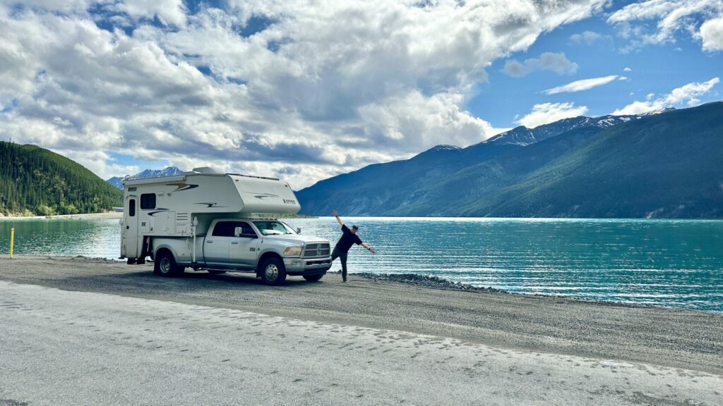 A man standing outside of his truck camper by Muncho Lake