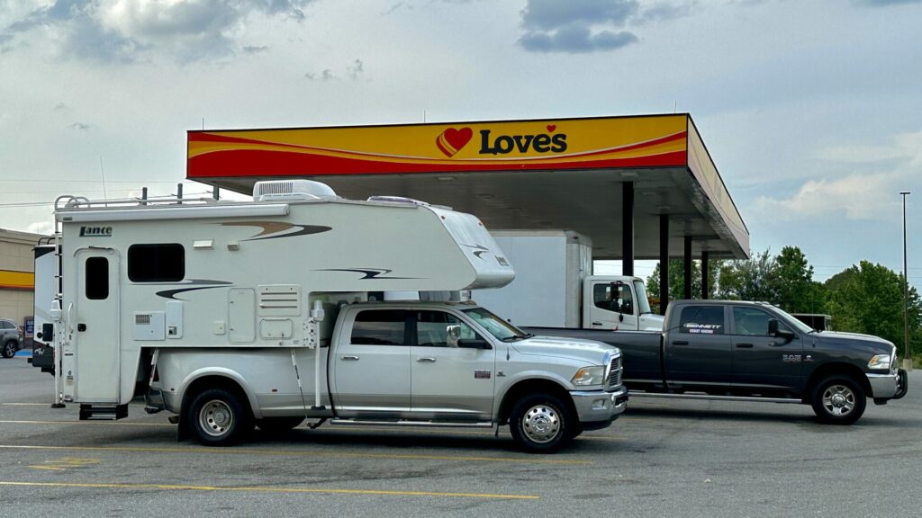 A truck with a truck camper attached to it parked at a Love's gas station during a cross country roadtrip