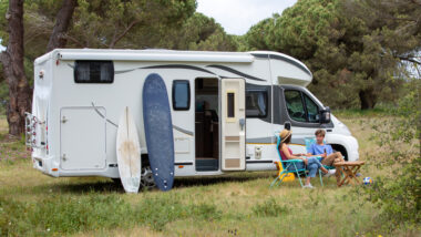 A couple sitting outside of their RV at their campsite that they secured using their escape membership
