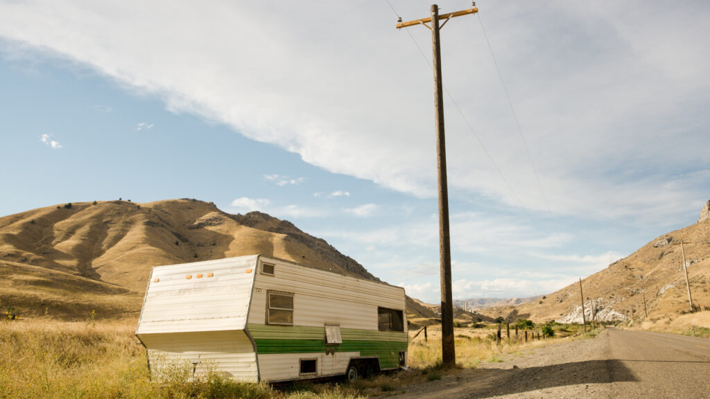 An older RV parked on the side of the road with straight lines painted on the side