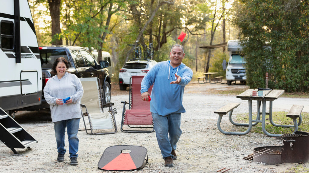 A couple playing corn hole at their seasonal campground