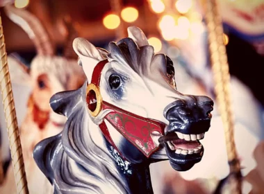 Close up of the neighing head of a carousel horse at an amusement park.