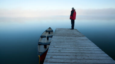 A man standing at the end of a dock at a lake in Riding Mountain National Park