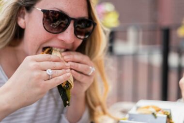 woman in sunglasses enjoying tacos at an outdoor taco shop