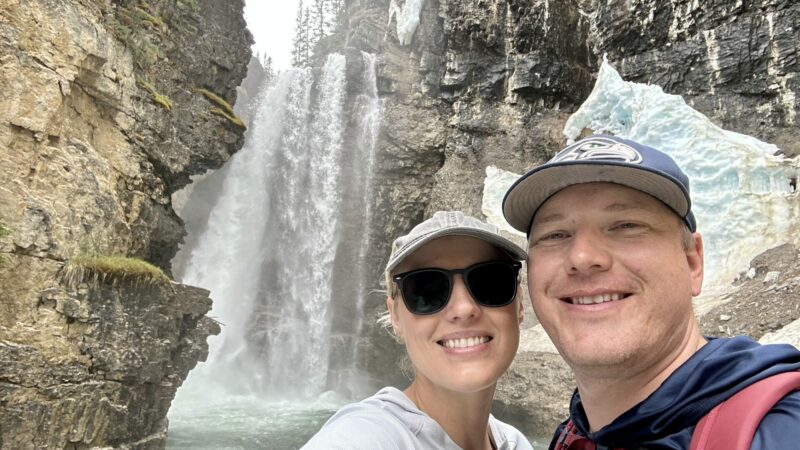 A couple taking a selfie at a waterfall at Johnston Canyon hike in Banff National Park