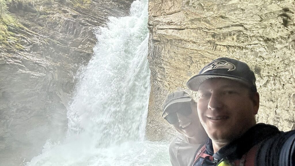 A couple taking a selfie at a waterfall at Johnston Canyon hike in Banff National Park