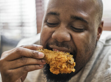 Man eating a piece of fried chicken