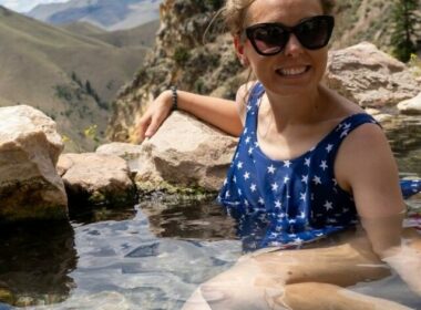 A woman in a patriotic swim suit soaks in the hot springs with a beautiful view over the mountains in Idaho.