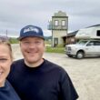 A couple smiling in Dawson City outside by their truck camper.