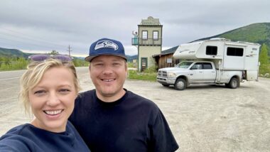 A couple smiling in Dawson City outside by their truck camper.
