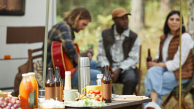 A group of friends sitting together drinking and singing at a tailgating RV party.