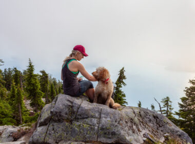 A woman sitting with her dog in a national park.