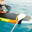 A paddle resting on a paddle board in aquamarine waters