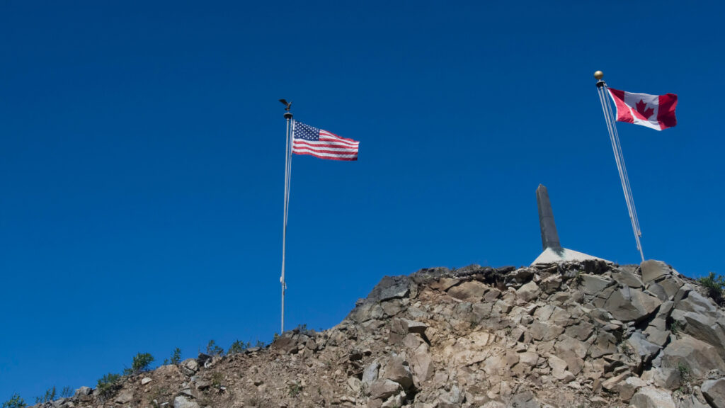 An American and Canadian flag at the Alaska-Canada border.