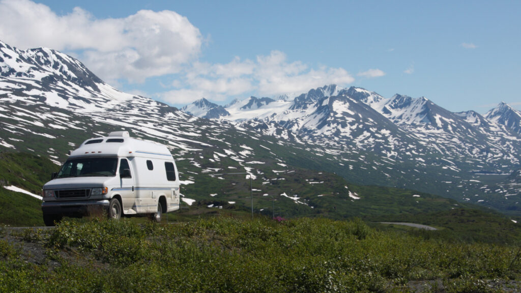 An camper van driving in Alaska to a campsite.
