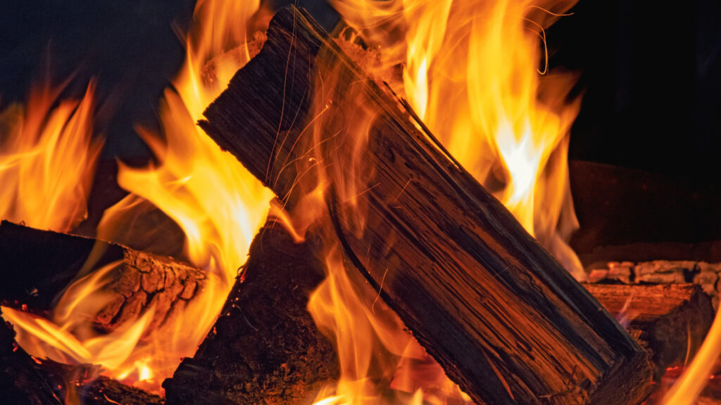 Close up of leftover campfire wood burning at a campsite.