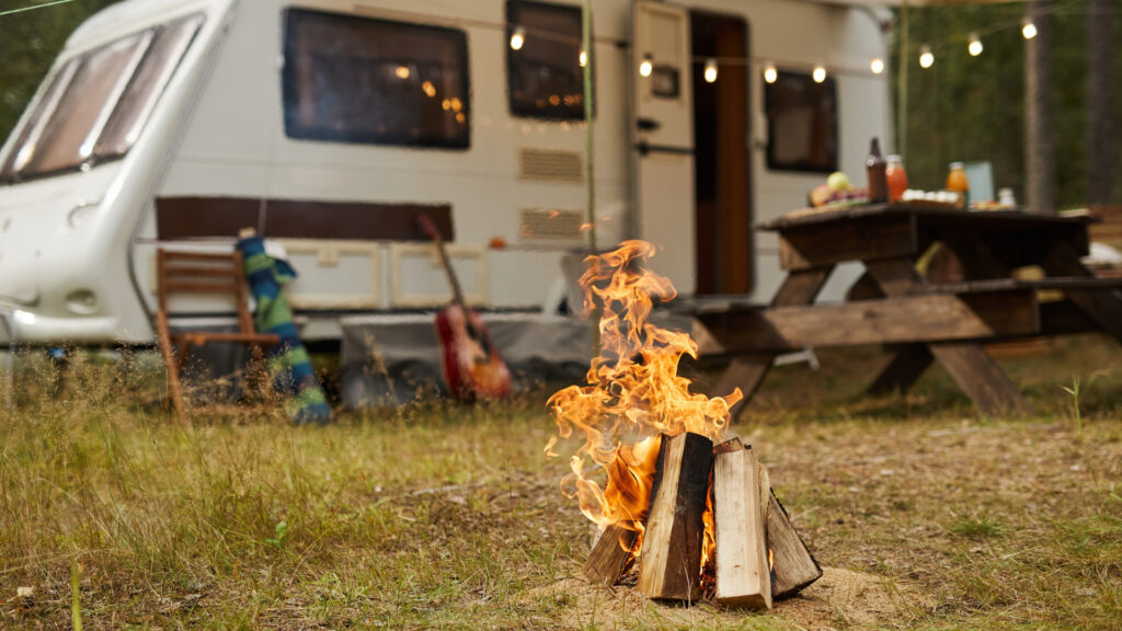 A campfire burning in front of an RV using leftover firewood.