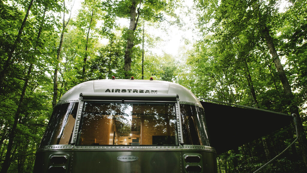 An Airstream Flying Cloud parked in the woods on a camping trip.