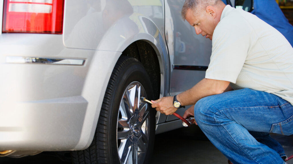 A man checking the tire pressure on his RV tires.