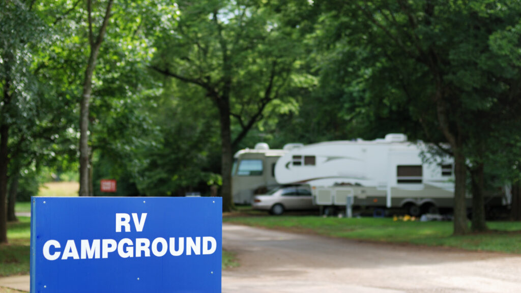 An RV campground sign in front of RVs.