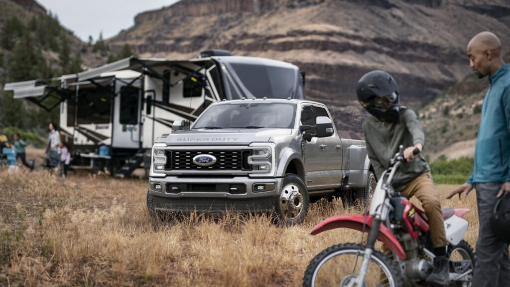 A Ford F-250 Super Duty truck parked at a campsite by an RV.