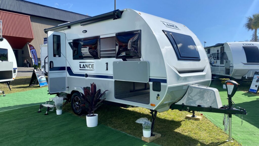 A small Lance travel trailer at an RV show ready for walkthroughs 