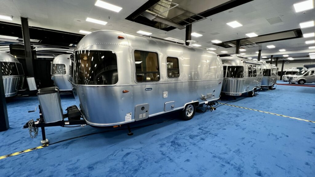 An Airstream travel trailer inside at an RV show with blue carpet 