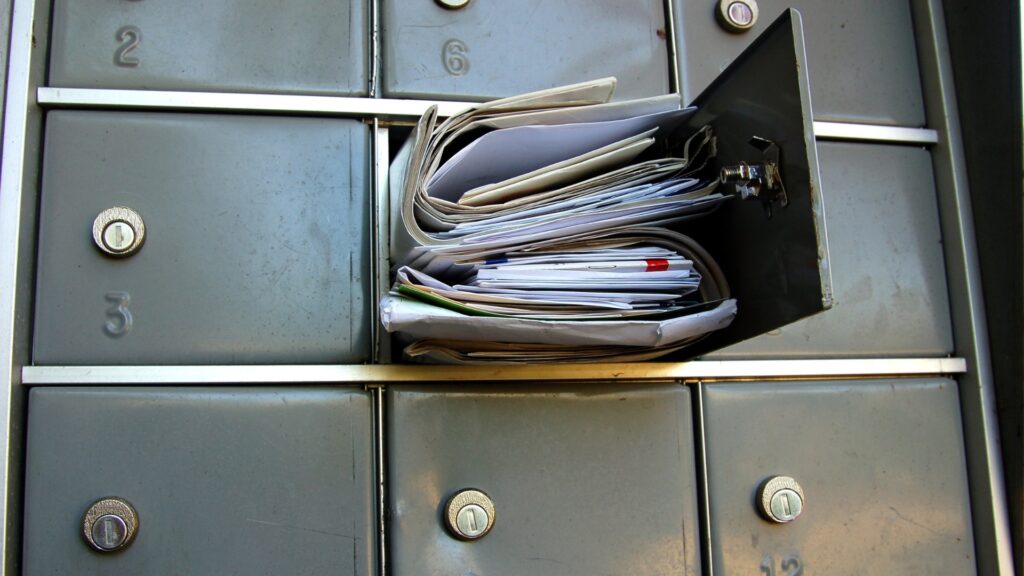 A mail forwarding service box that is overflowing with junk mail 