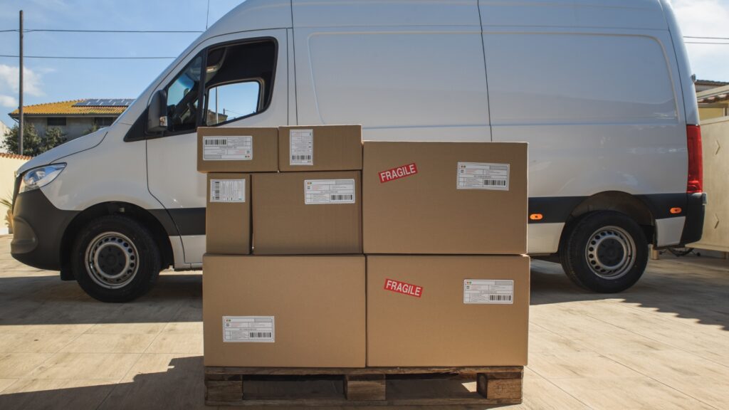 A van with a pallet of boxed in front of it ready to be loaded and shipped 