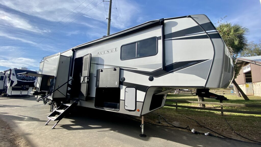 Outside shot of an Alliance Avenue fifth wheel with open storage bays.