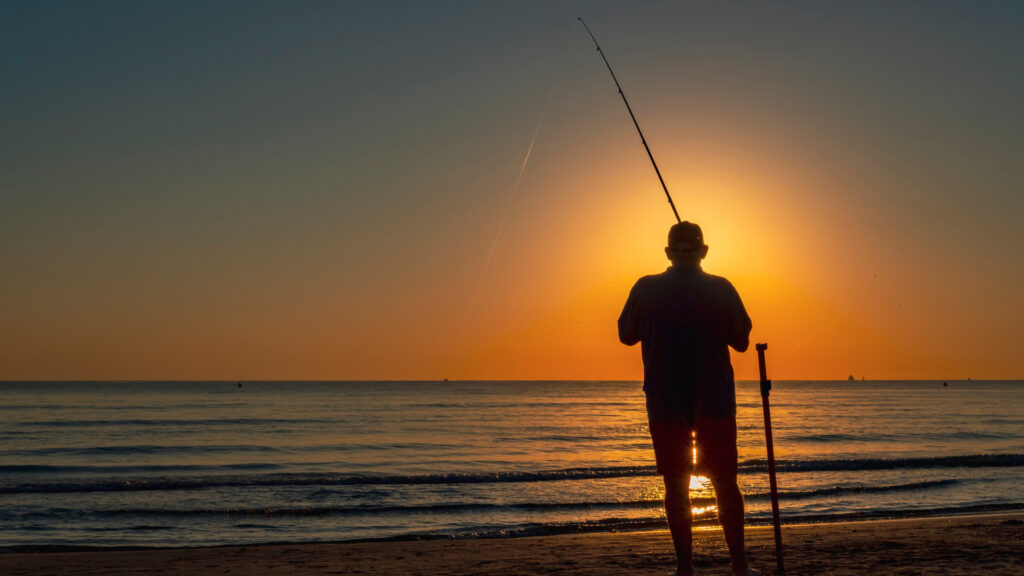 A man using his Florida fishing license to fish during sunset.