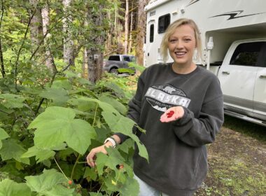 A woman holding up wild berries in Alaska.