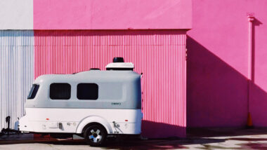 A clean fiberglass camper after using an oxidation remover, parked outside of a pink wall