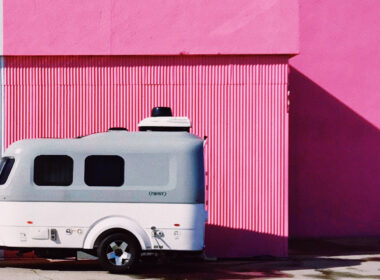 A clean fiberglass camper after using an oxidation remover, parked outside of a pink wall