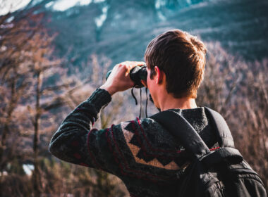 A man using binoculars in a national park to watch wildlife.