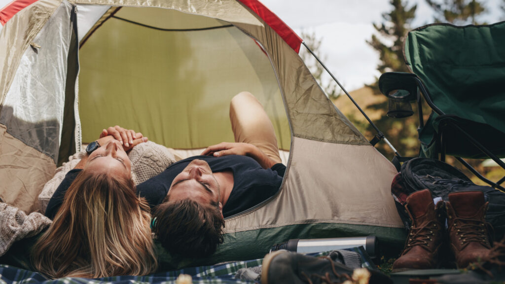 A couple laying together in their camping tent. 