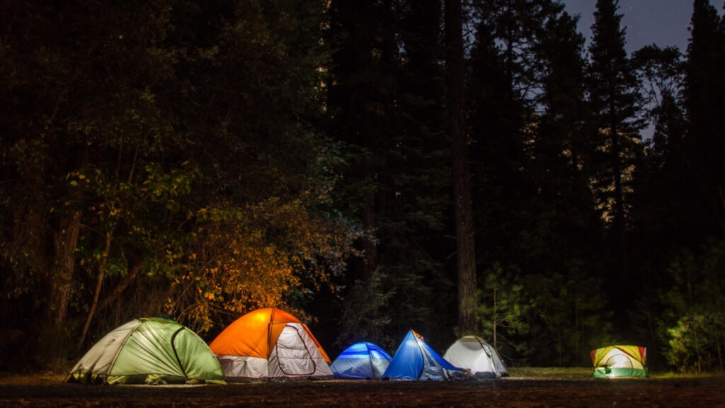 Tents gathered together at night during a group camping trip.