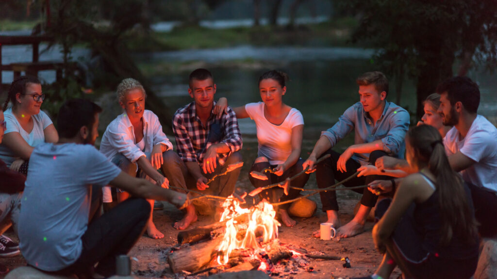 A group of friends on a group camping trip sitting around the campfire.