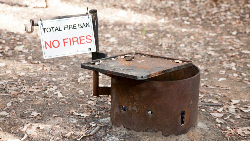 A sign on a firepit that says "total fire ban. No fires".