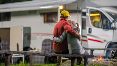 A father and daughter sitting outside of their RV.