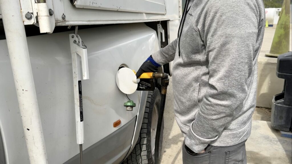 Jason adding diesel fuel to the truck with the truck camper loaded, before we head down the Cassiar Highway.