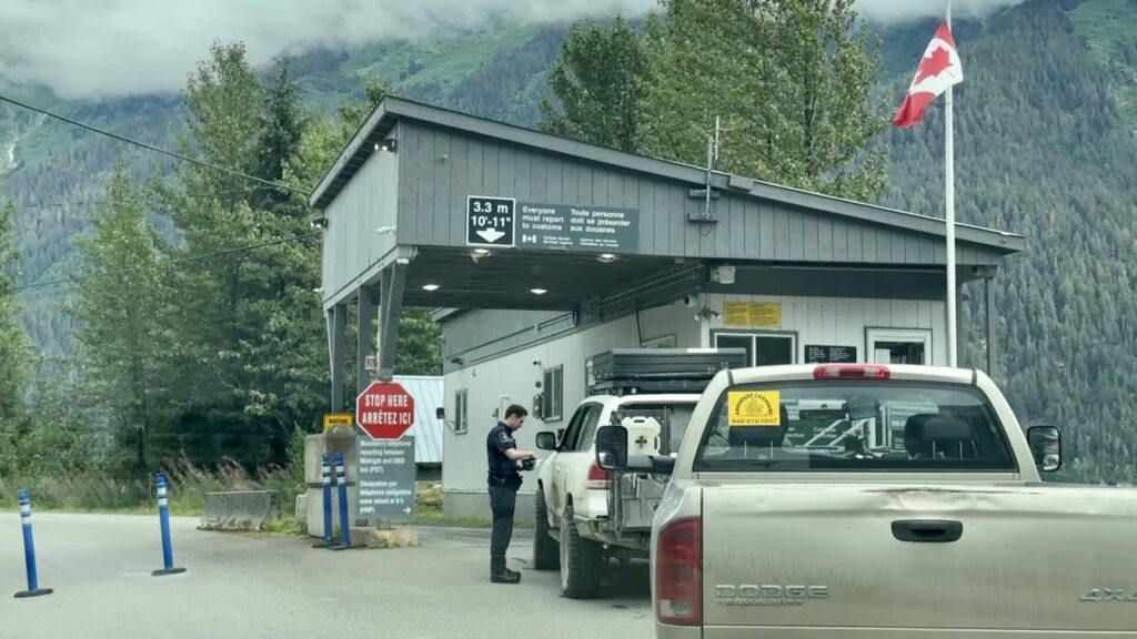 A Canadian border agent looking at some papers in front of the Stewart Hyder border crossing. 