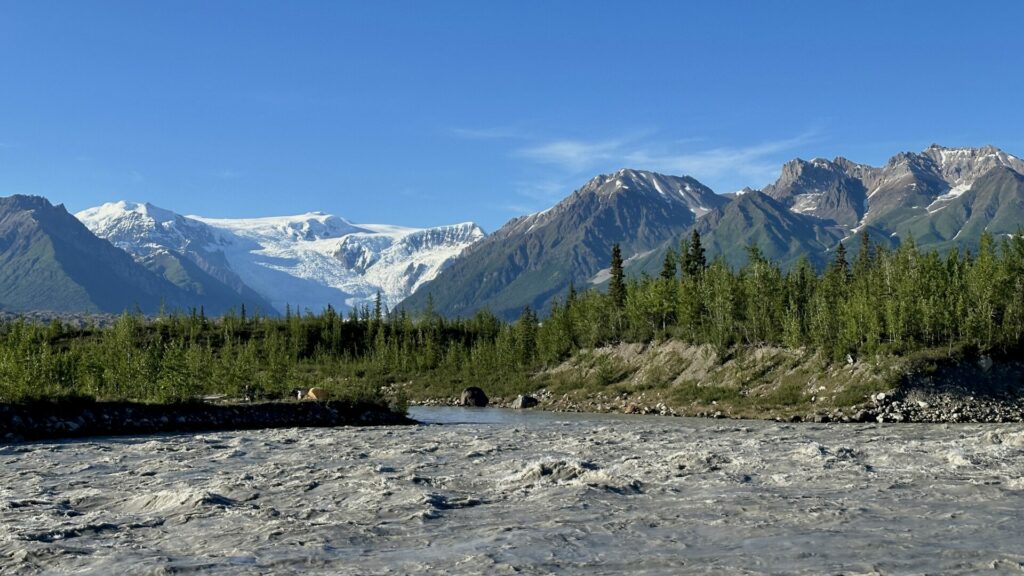 A glacier in the distance with water flowing in the foreground inside the Wrangell Mountains.