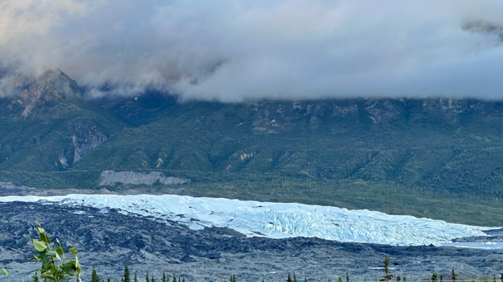 The Matanuska Glacier with green mountains and thick clouds in the background. This is one of the most popular glaciers in Alaska due to its accessibility. 