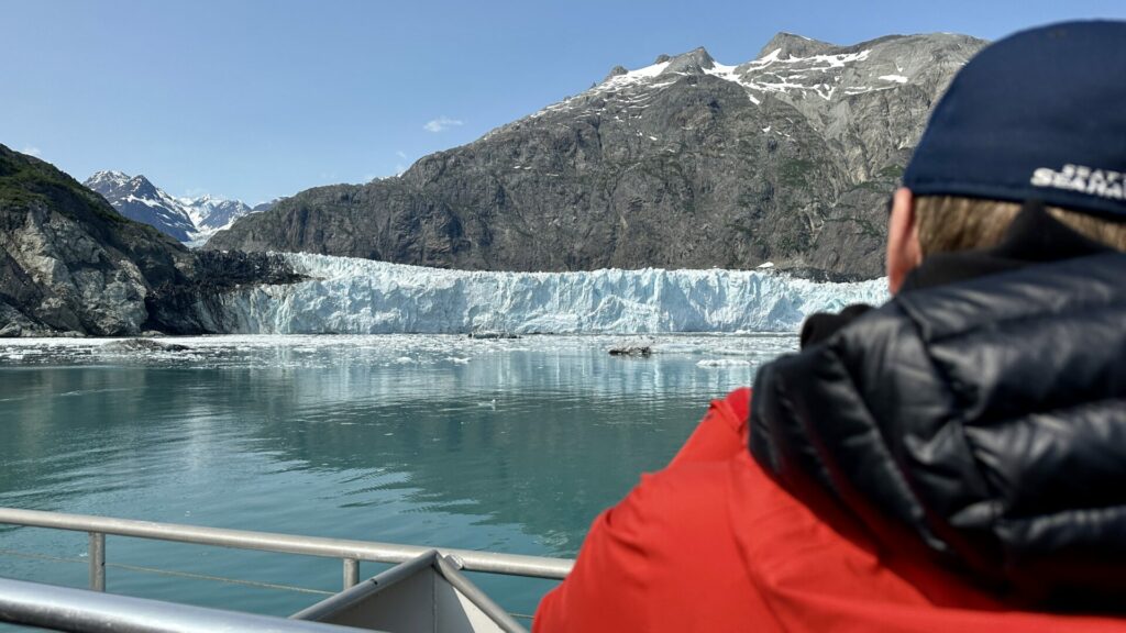 A man on a boat looking at one of the glaciers in Alaska, Margerie Glacier. 