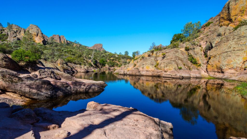 The Bear Gulch area of Pinnacles National Park, with calm waters and clear blue skies. 