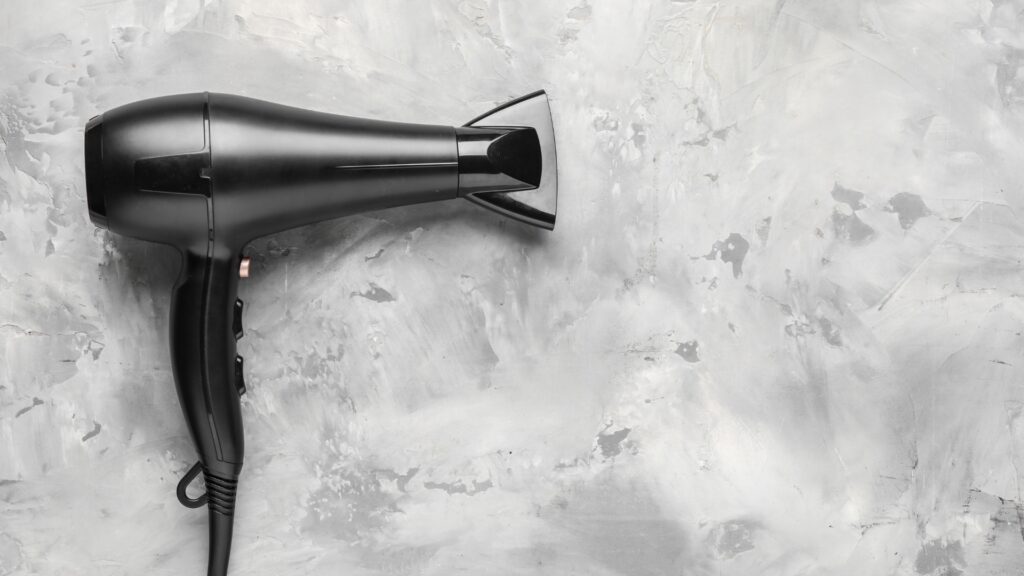 A blow dryer on a slate background.