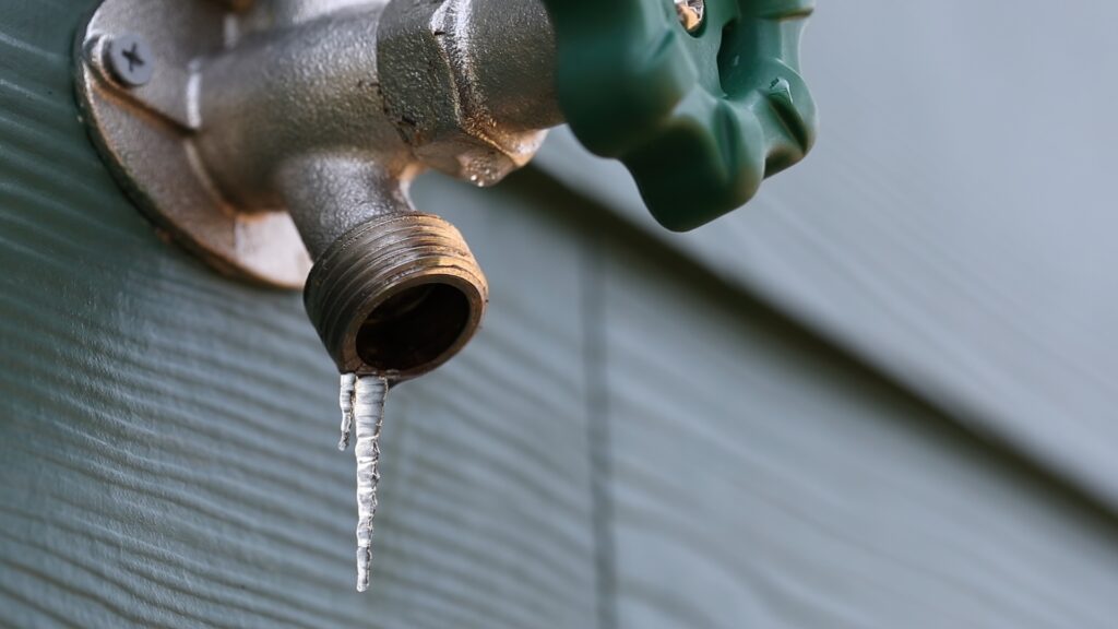 An outdoor faucet with a frozen drip coming out of it. 